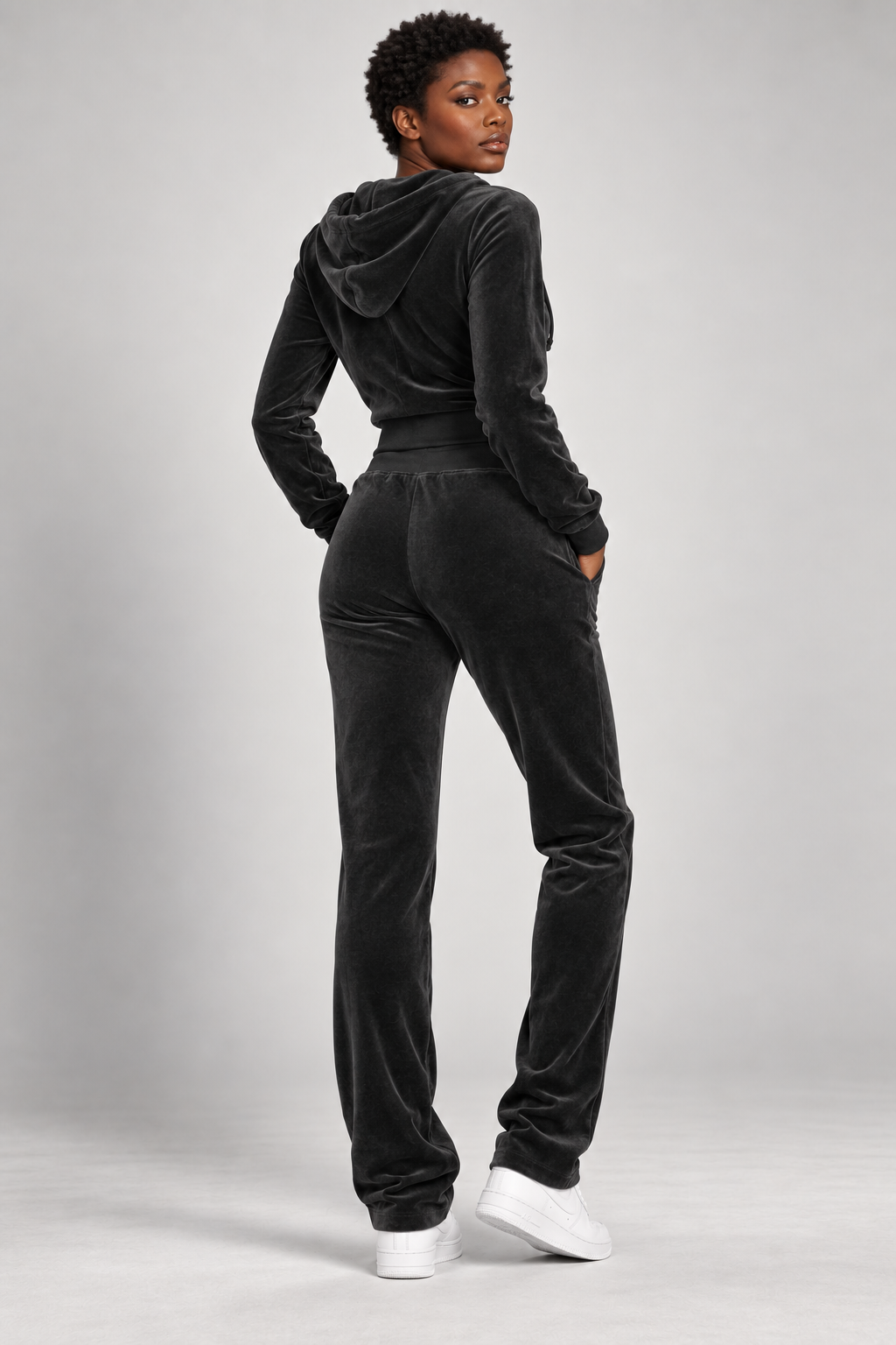 High-fashion model wearing The Icon Velour Hooded Set in black, back view